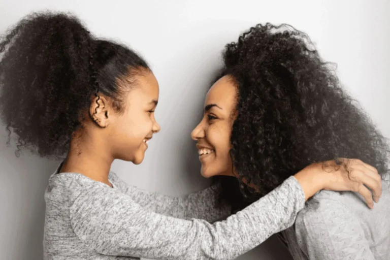 Smiling mother and daughter face each other and embrace, symbolizing trust and openness in teaching anatomically correct terms.